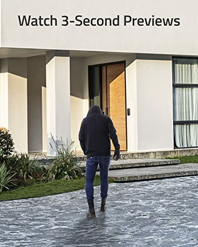 Person in dark clothing walking towards a modern building for smart home security